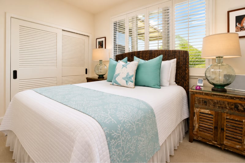 Guest bedroom at Wailea Beach Villas PH505 — woven headboard with coral bedspread and mirrored closet doors WBV-PH505