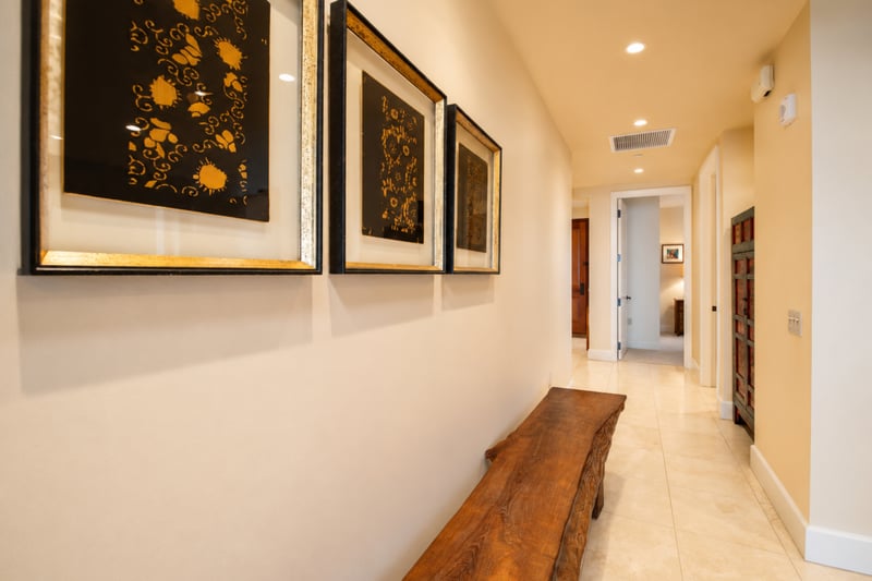 Hallway gallery at Wailea Beach Villas PH505 — framed Asian textile art above a live-edge wood bench WBV-PH505