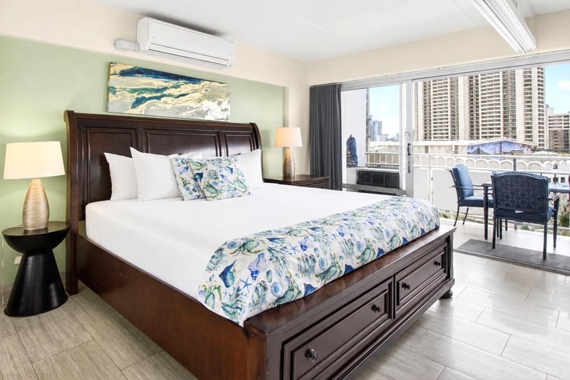 Spacious bedroom area featuring a king-size bed, tropical decor, and abundant natural light. ILK-732