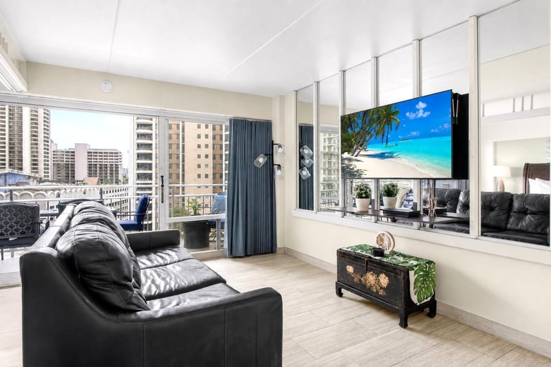 Bright open-concept living room with floor-to-ceiling windows, comfortable seating, and stunning city and ocean views. ILK-732
