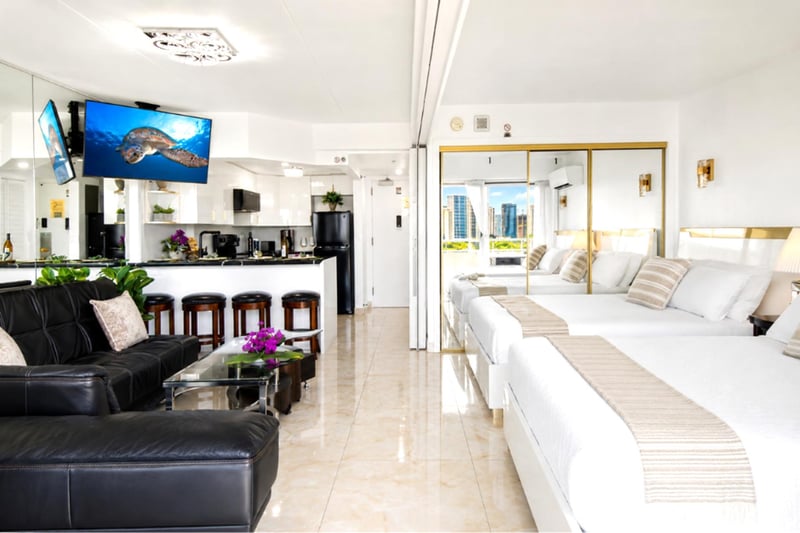 Bright, open-plan living with polished marble floors, plush leather seating, a full breakfast bar, and a wall-mounted Smart TV - the whole suite bathed in island light.