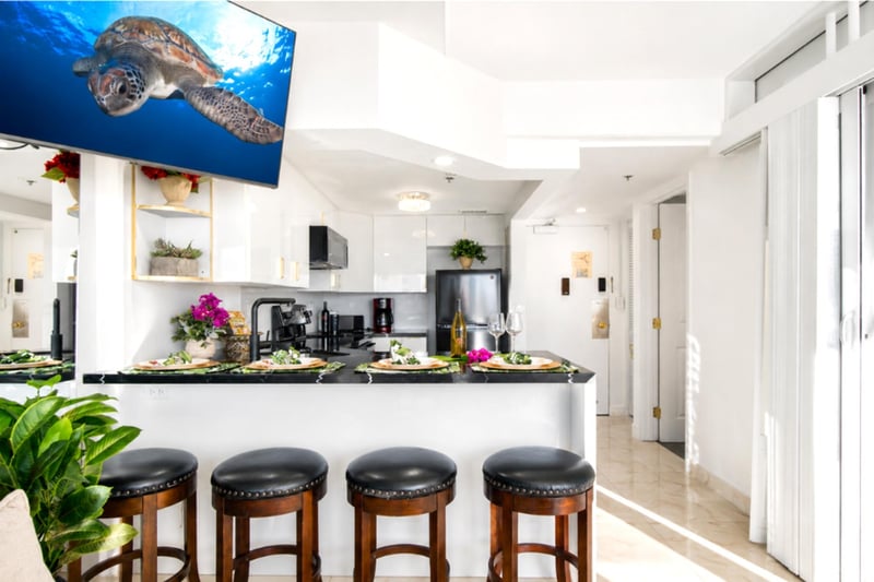 Casual island dining at the breakfast bar, with the full kitchen and entry just beyond.