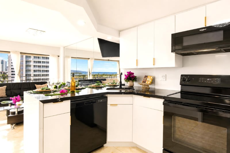 A sleek, fully stocked kitchen with black-granite counters, full-size range and dishwasher, and an ocean view through the window while you cook.