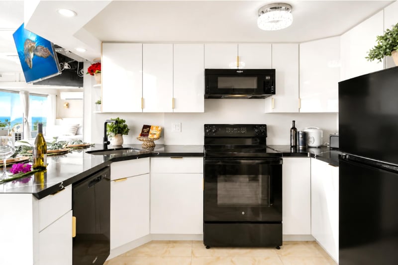 Everything a home chef needs - full-size oven, microwave, and refrigerator, ample white cabinetry, and a bright breakfast bar opening to the living space.