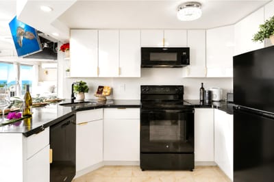 Everything a home chef needs - full-size oven, microwave, and refrigerator, ample white cabinetry, and a bright breakfast bar opening to the living space.
