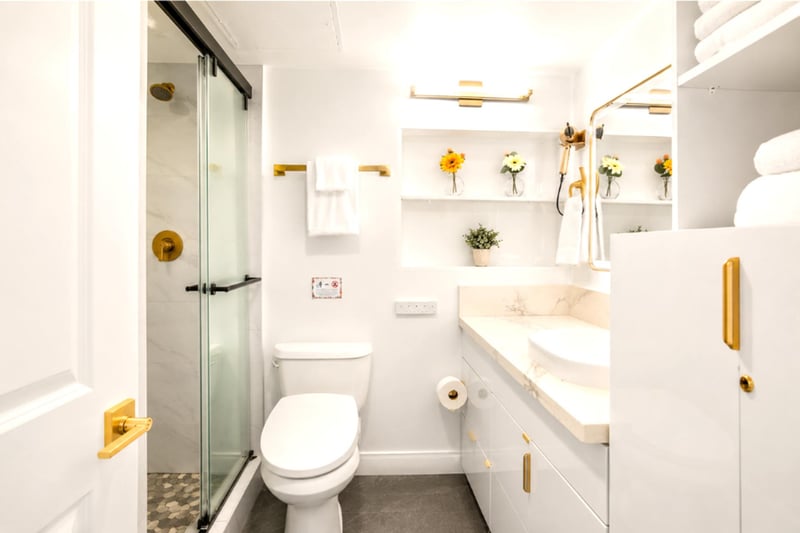 Spa-style bathroom with a glass walk-in rain shower, marble-topped vanity and vessel sink, gold fixtures, and plush KBM towels.