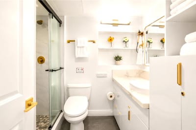 Spa-style bathroom with a glass walk-in rain shower, marble-topped vanity and vessel sink, gold fixtures, and plush KBM towels.