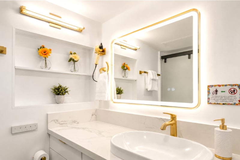 Get ready in style at the marble vanity beneath a backlit gold mirror - vessel sink, gold tapware.
