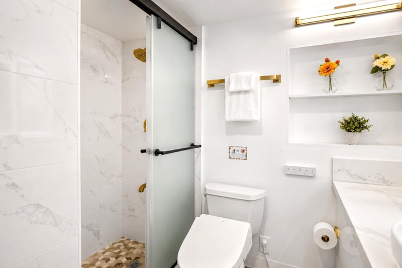 Marble-clad walk-in shower and clean, bright finishes stocked with plush KBM towels - a fresh, modern bath for two.