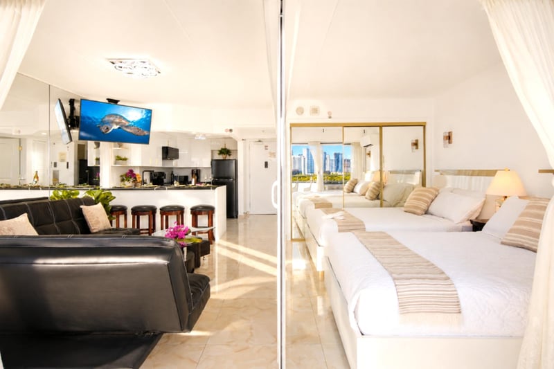 The full open-plan layout at a glance - leather lounge, breakfast bar, and two queen beds flowing out to the lanai and Waikiki views beyond.