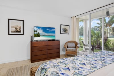 Spacious primary bedroom with dresser, smart TV and private lanai access