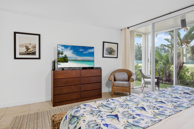 Spacious primary bedroom with dresser, smart TV and private lanai access
