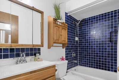 Step into a cozy retreat where rich navy tiles and warm wood finishes meet in a perfect splash of retro hospitality