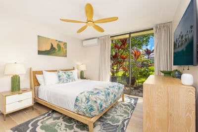 The bedroom on the main floor of this condo has floor-to-ceiling glass sliders and a Queen-size bed. KUL-W11