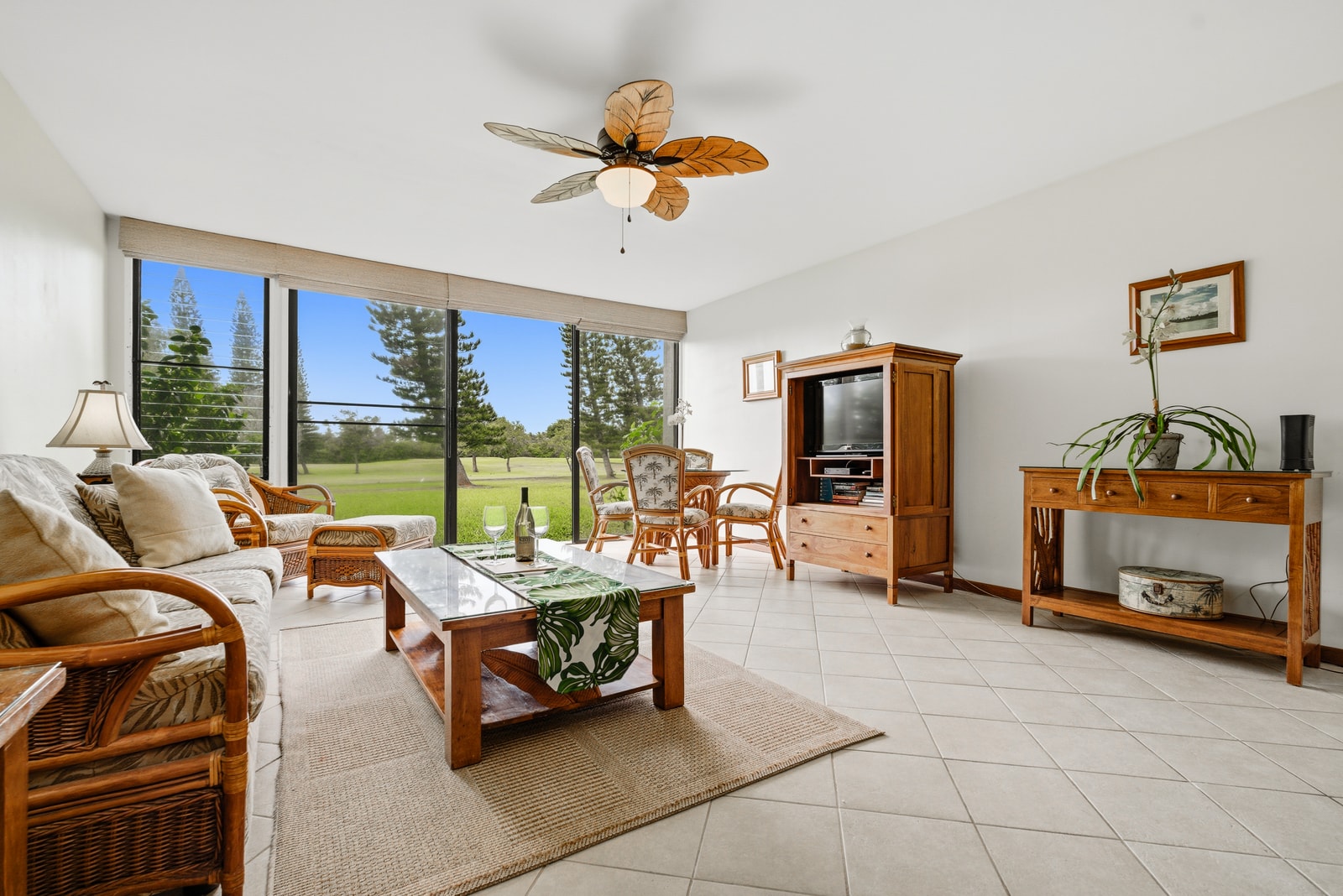 Open-concept living area with tropical rattan furnishings and seamless flow to the lawn beyond.