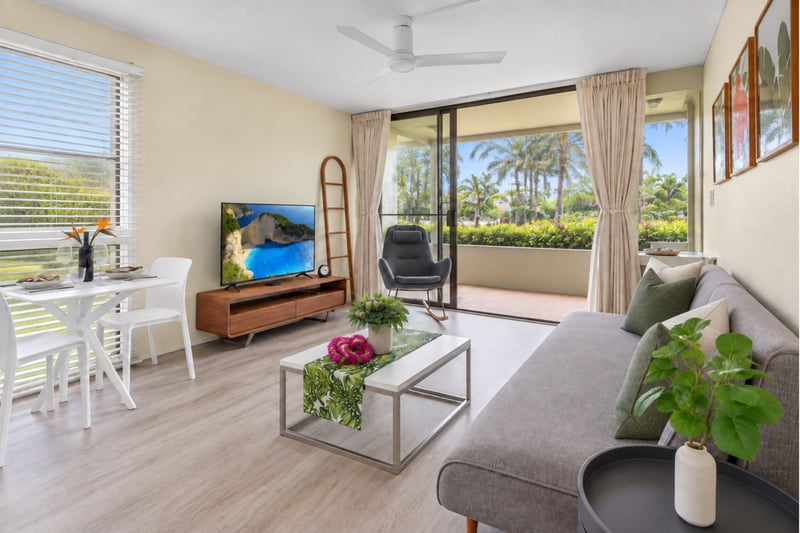 Living room seating at Kuilima West Estates 144, with a smart TV, ceiling fan, and direct lanai access for indoor-outdoor living.