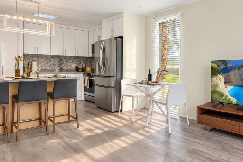 Kitchen and dining nook at Kuilima West Estates 144, with a second dining table and wall-mounted TV alongside the full kitchen.