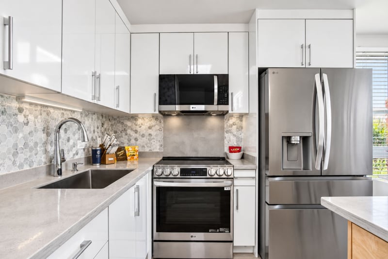 Chef's kitchen at Kuilima West Estates 144, with stainless LG appliances, quartz counters, and a hexagon marble backsplash.