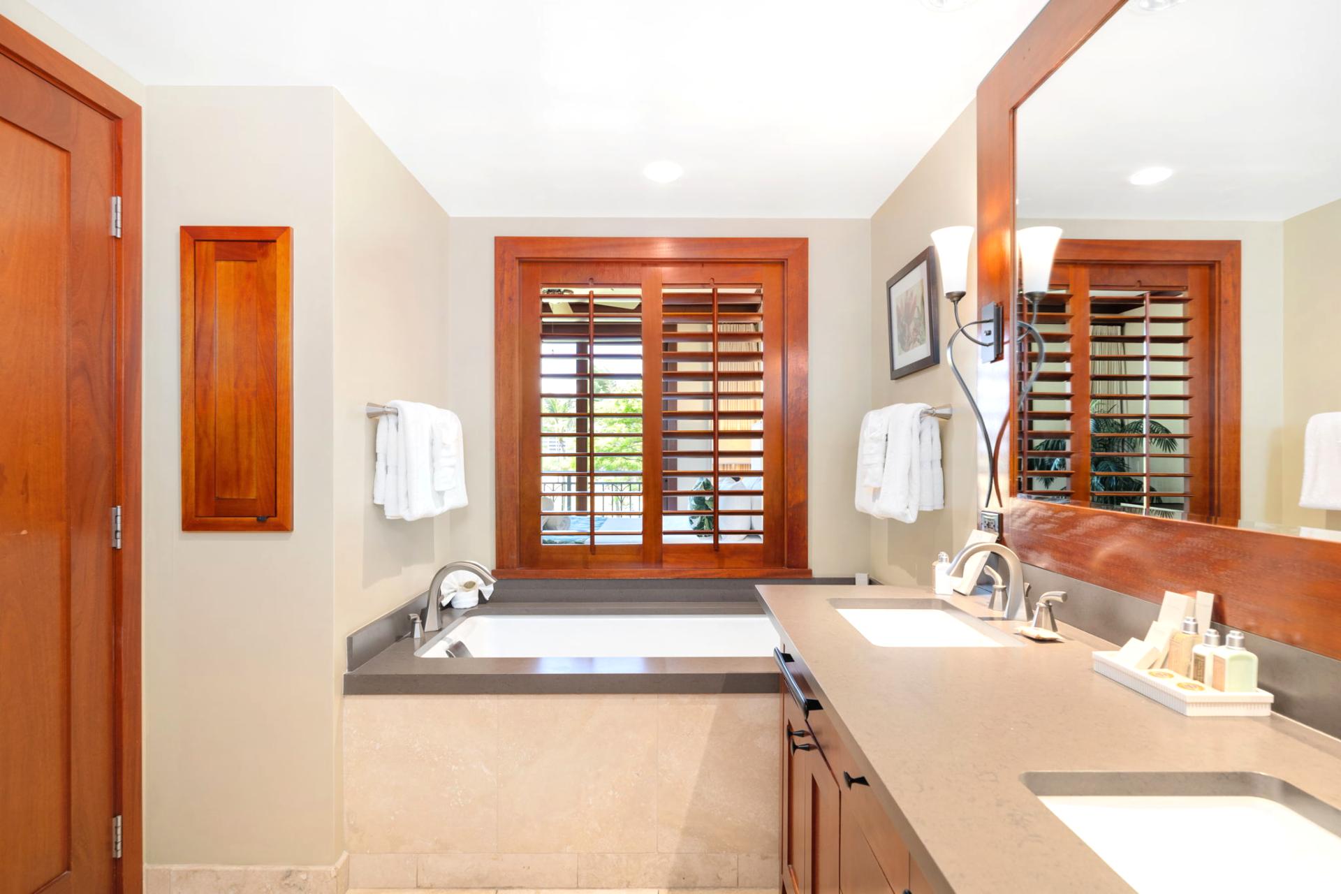 Spacious and sunlit, this guest bath welcomes with dual vanities, plush towels, and a hint of upscale island flair    
