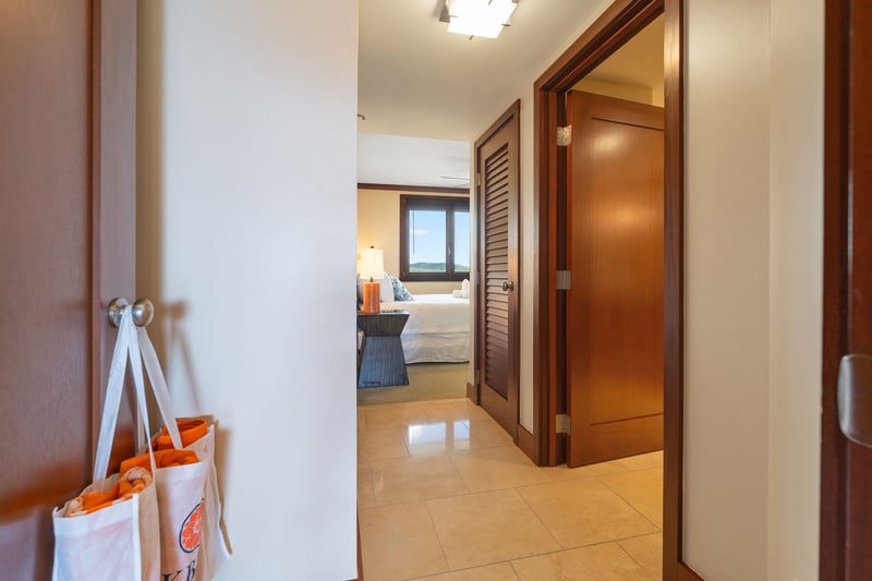 Just beyond the hallway's soft glow lies your private haven—framed in rich wood, calm lighting, and island simplicity    