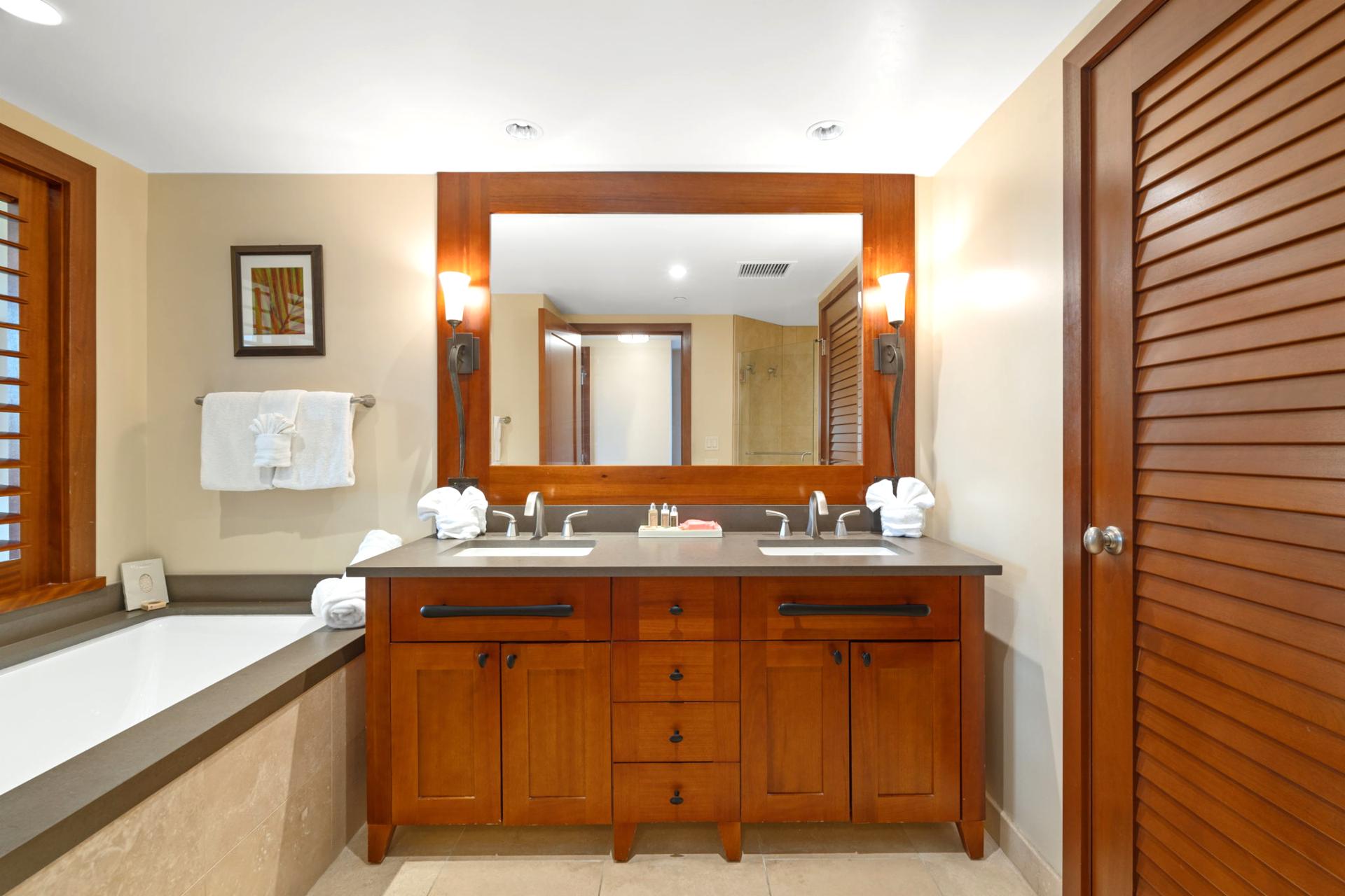The mirror stretches wide like a portal to paradise, reflecting double sinks, glowing wood, and self-care rituals    