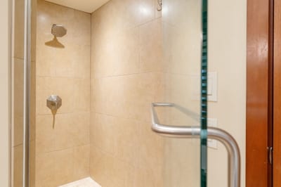 The walk-in shower stands ready like a sandstone throne room, awaiting its next royal rinse ceremony