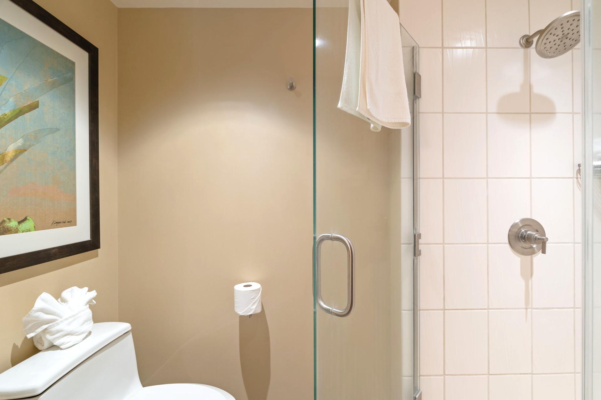 Even the toilet gets the luxury treatment here—topped with a bow-tied towel and watched over by breezy artwork    