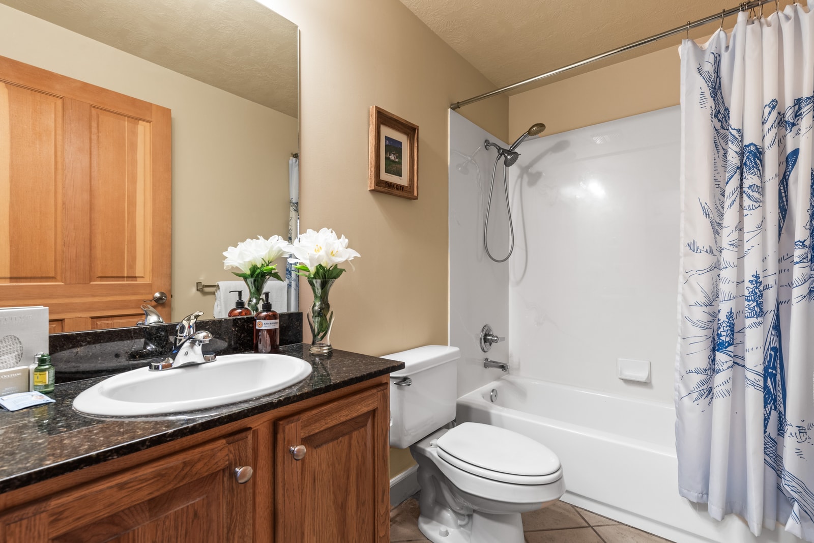 Full guest bath includes granite vanity, L’Occitane amenities, and a shower/tub combo.