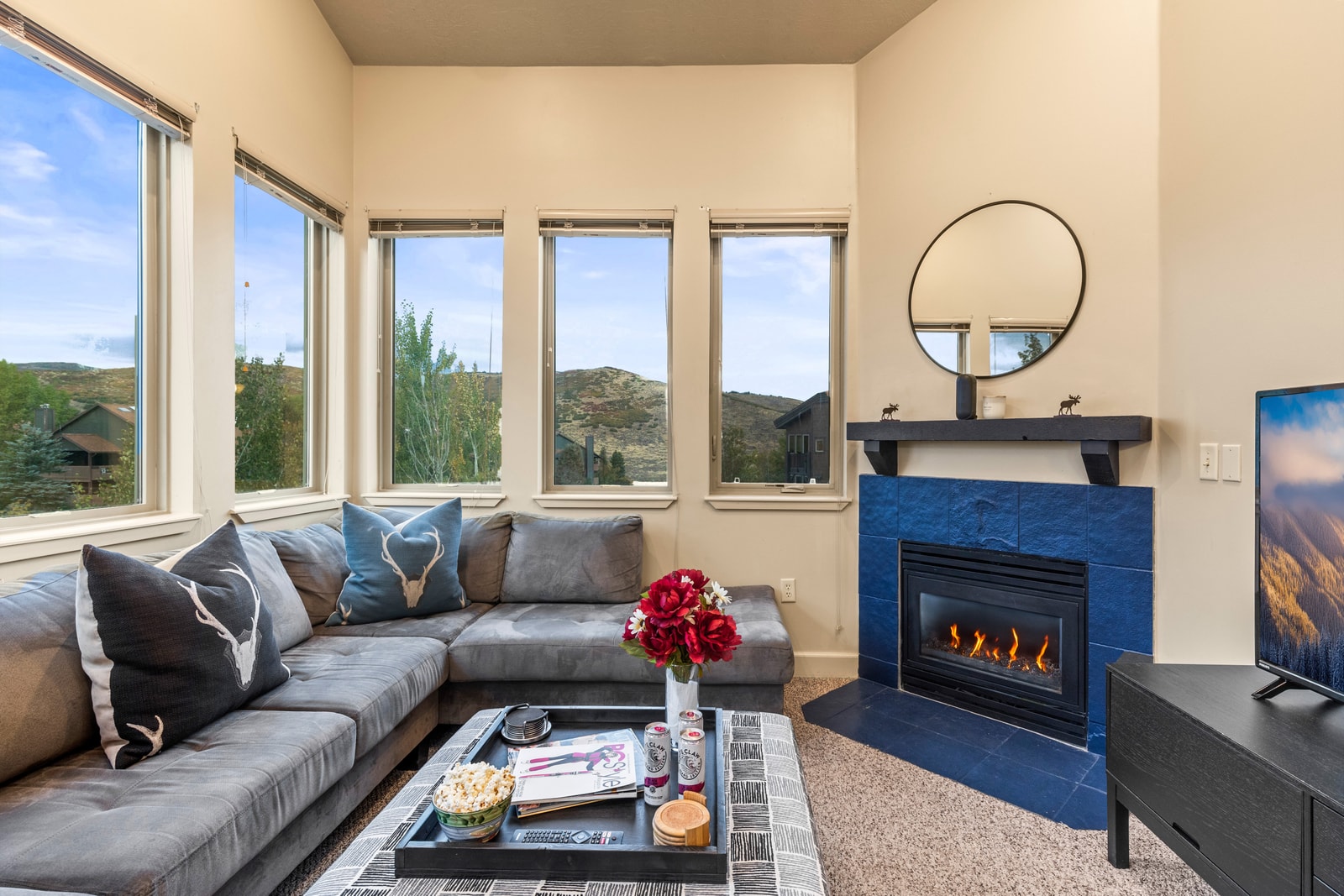 Spacious living area with wraparound windows, Smart TV, and gas fireplace offers comfort and connection.