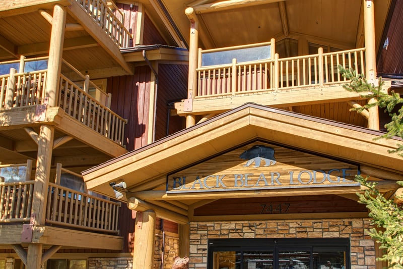 Exterior shot of Black Bear Lodge with covered entry, rustic beams, and mountain lodge style.