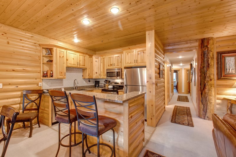 Cabin-style kitchen with log walls, full appliances, and charming touches throughout.