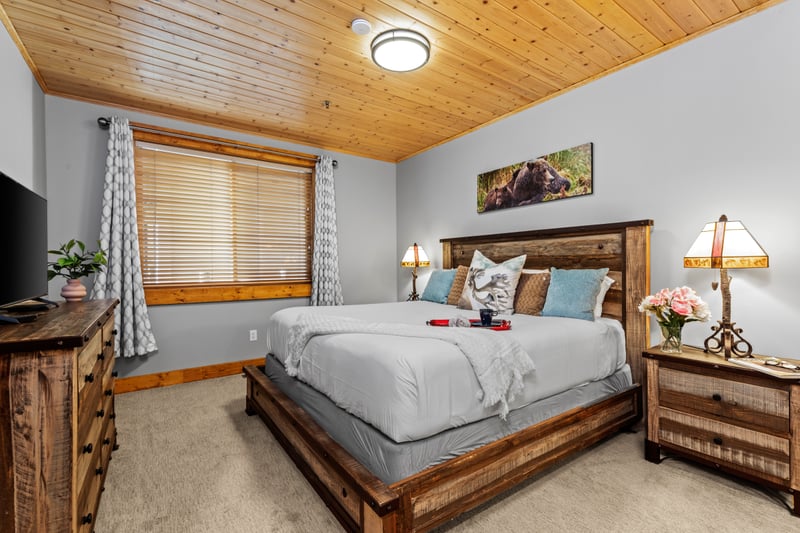 Retreat to the primary bedroom with a plush King bed, dresser, and warm lodge-style details for a restful night. BBL-351A