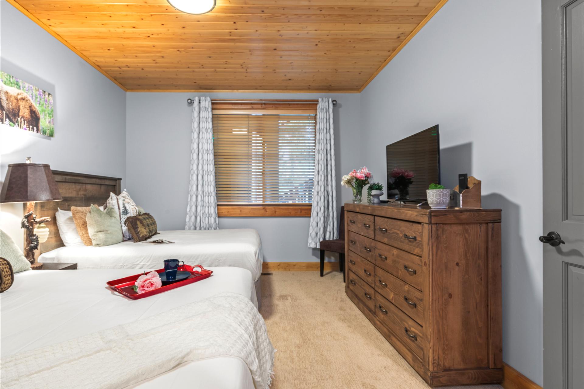 Guest bedroom with two Queen beds, ample storage, and warm wood ceilings for a restful retreat.
