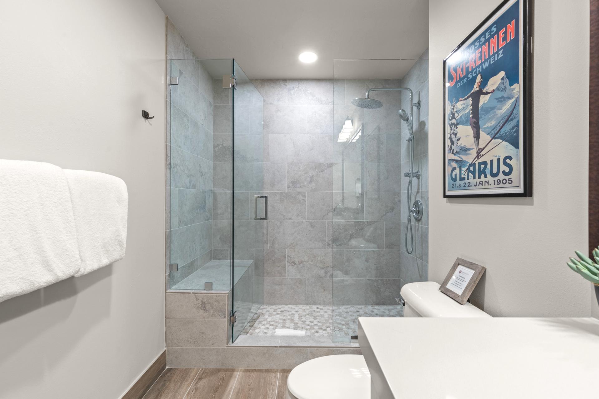 The second bathroom features a glass walk-in shower, full vanity, and tile flooring.