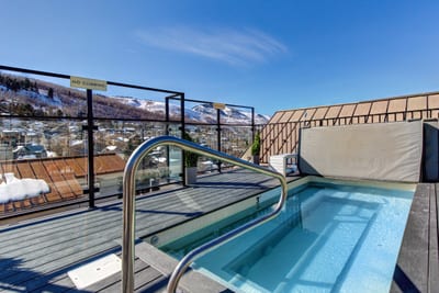 Hot tub with safety rail and views across the snowy rooftops and trees.