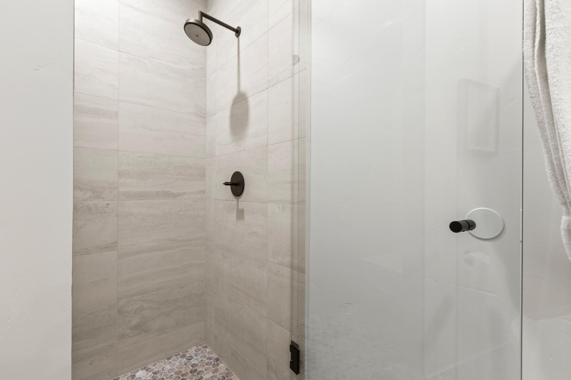 Step-in tub and white tile elevate the full bath shared by the bunk room.