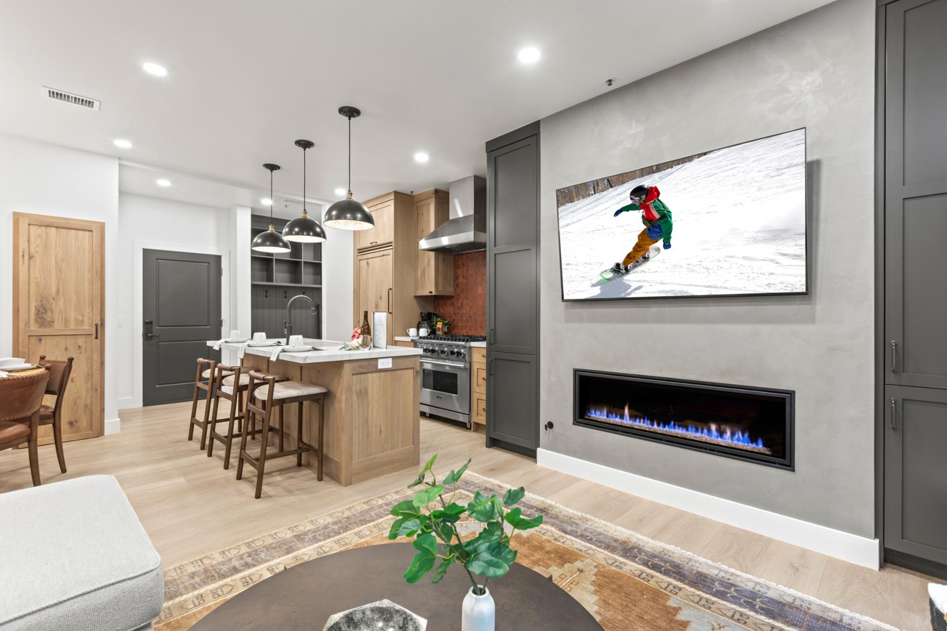 Cozy up in the living room with a wall-mounted Smart TV, modern fireplace, and open flow to dining and kitchen.