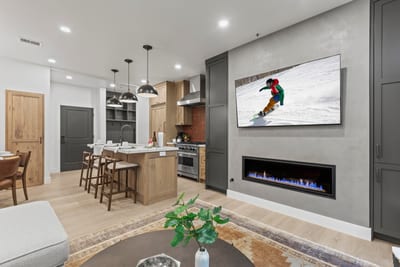 Cozy up in the living room with a wall-mounted Smart TV, modern fireplace, and open flow to dining and kitchen.