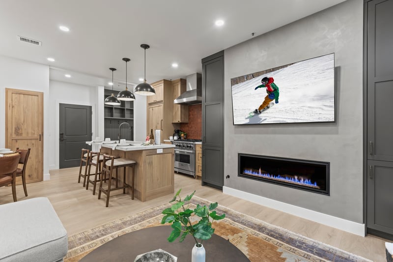 Cozy up in the living room with a wall-mounted Smart TV, modern fireplace, and open flow to dining and kitchen.