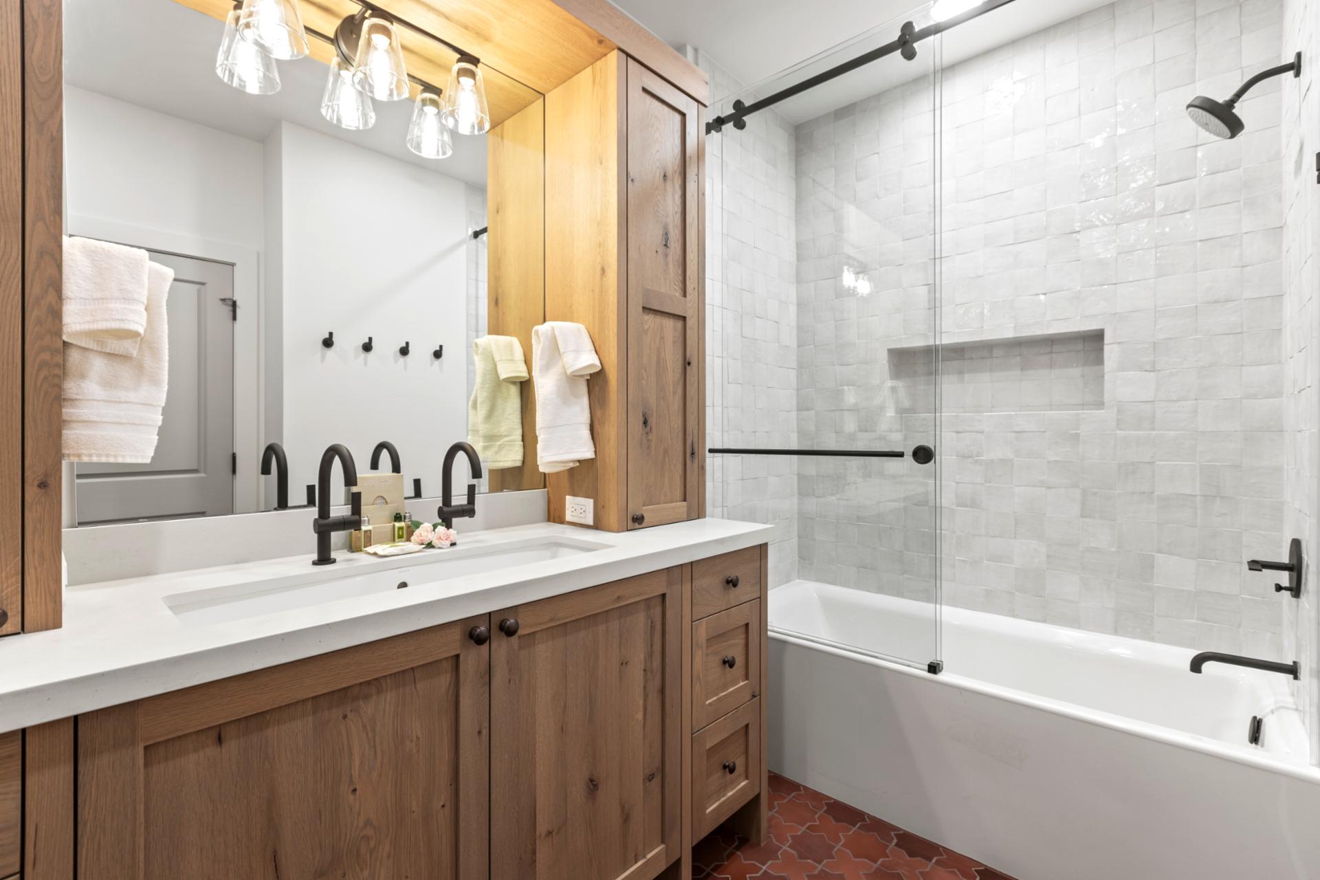 Full bath with shower/tub combo, wood cabinetry, and granite counter just outside the Queen bedroom.
