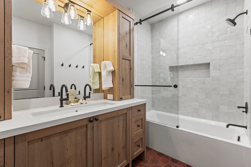 Full bath with shower/tub combo, wood cabinetry, and granite counter connected to the bunk room