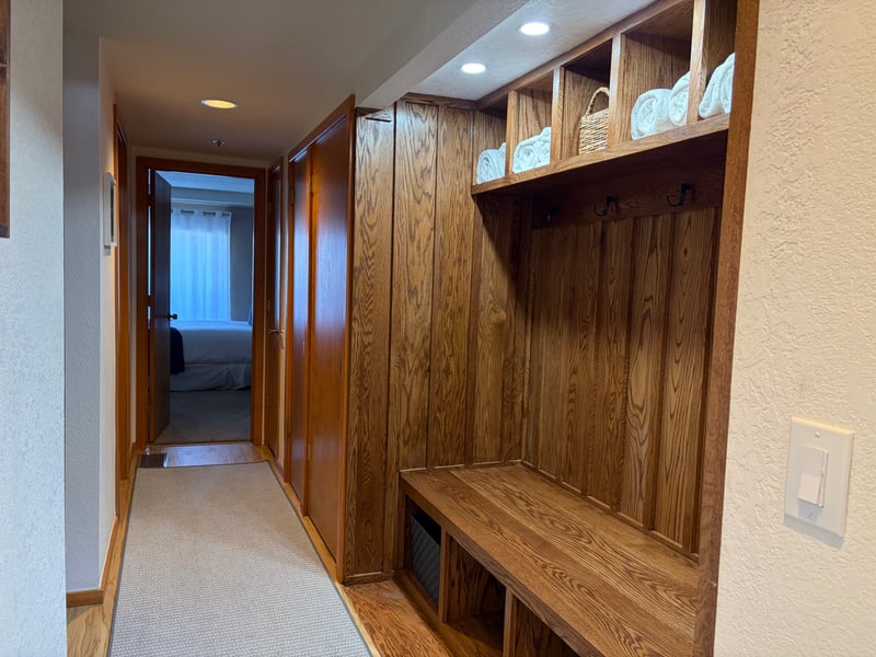 Ski mudroom entry — wood-paneled cubbies, boot bench, and folded towels for effortless gear drop-off