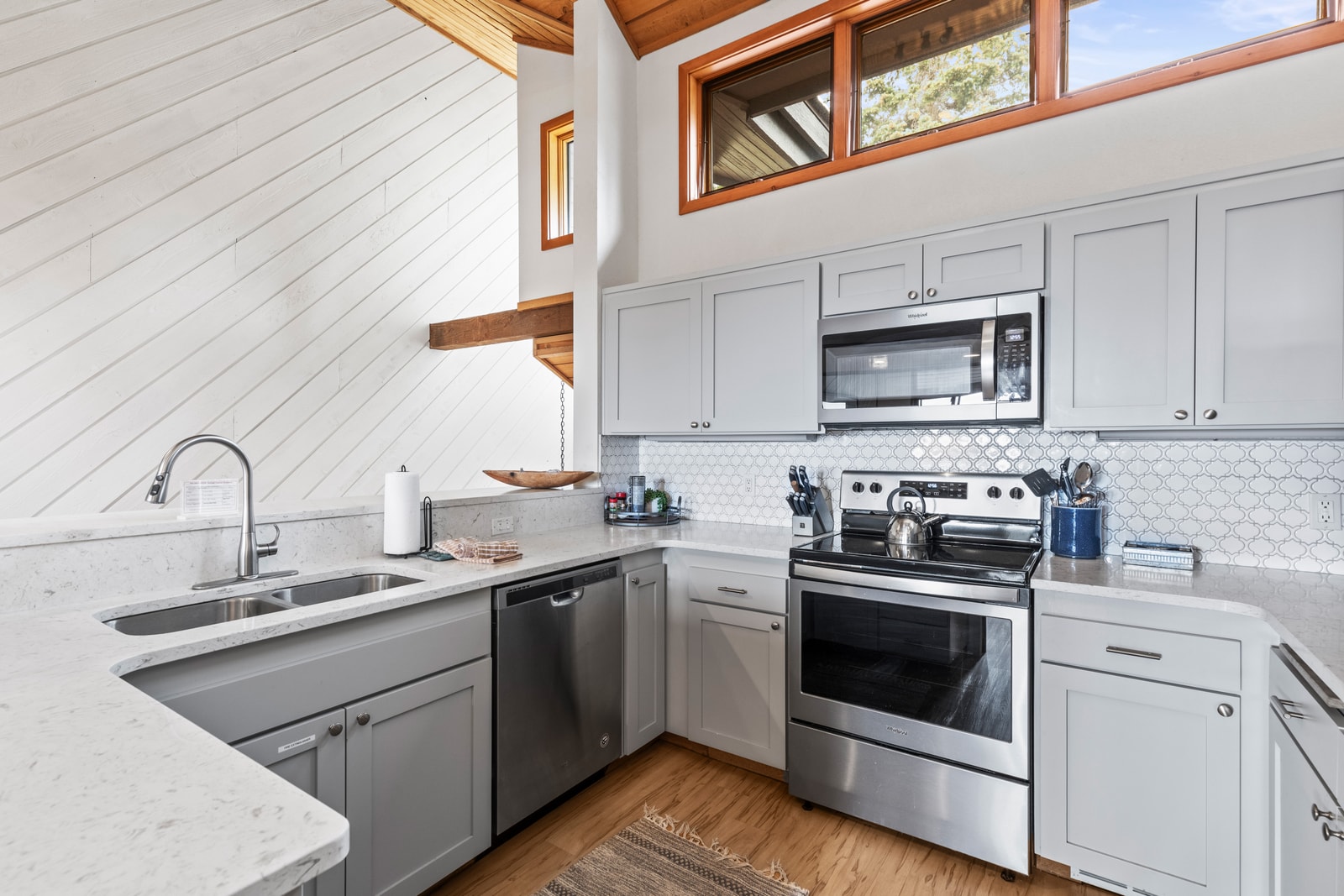 Fully equipped kitchen with stainless appliances, stone counters, and elevated breakfast bar seating.