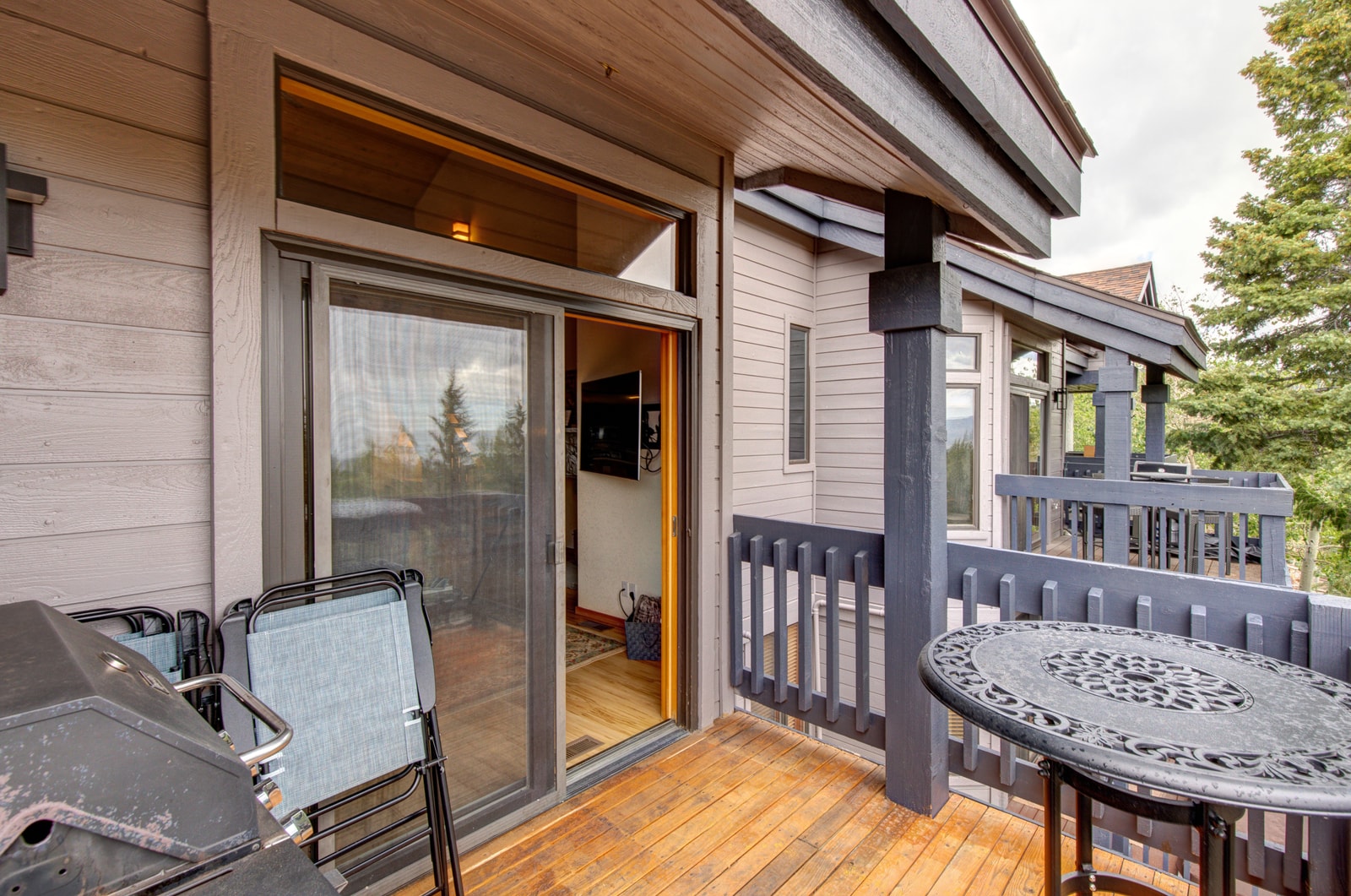 This spacious balcony includes outdoor seating and dining with a tree-lined view.