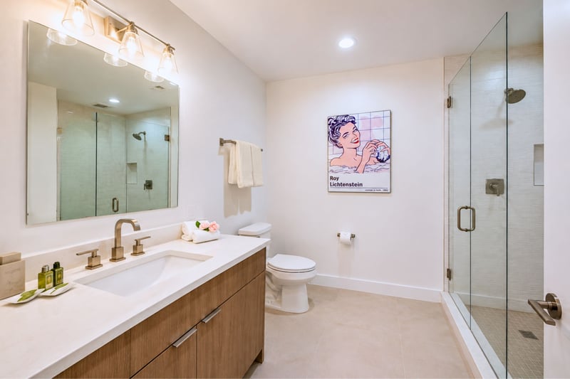 This full guest bath includes a separate glass-enclosed shower, a private water closet, and its own vanity.