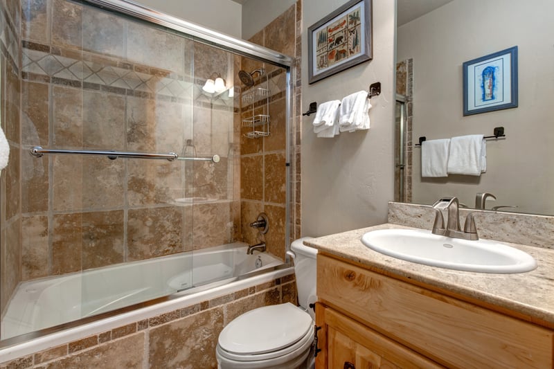 The guest bath includes a shower-tub combo, granite counter