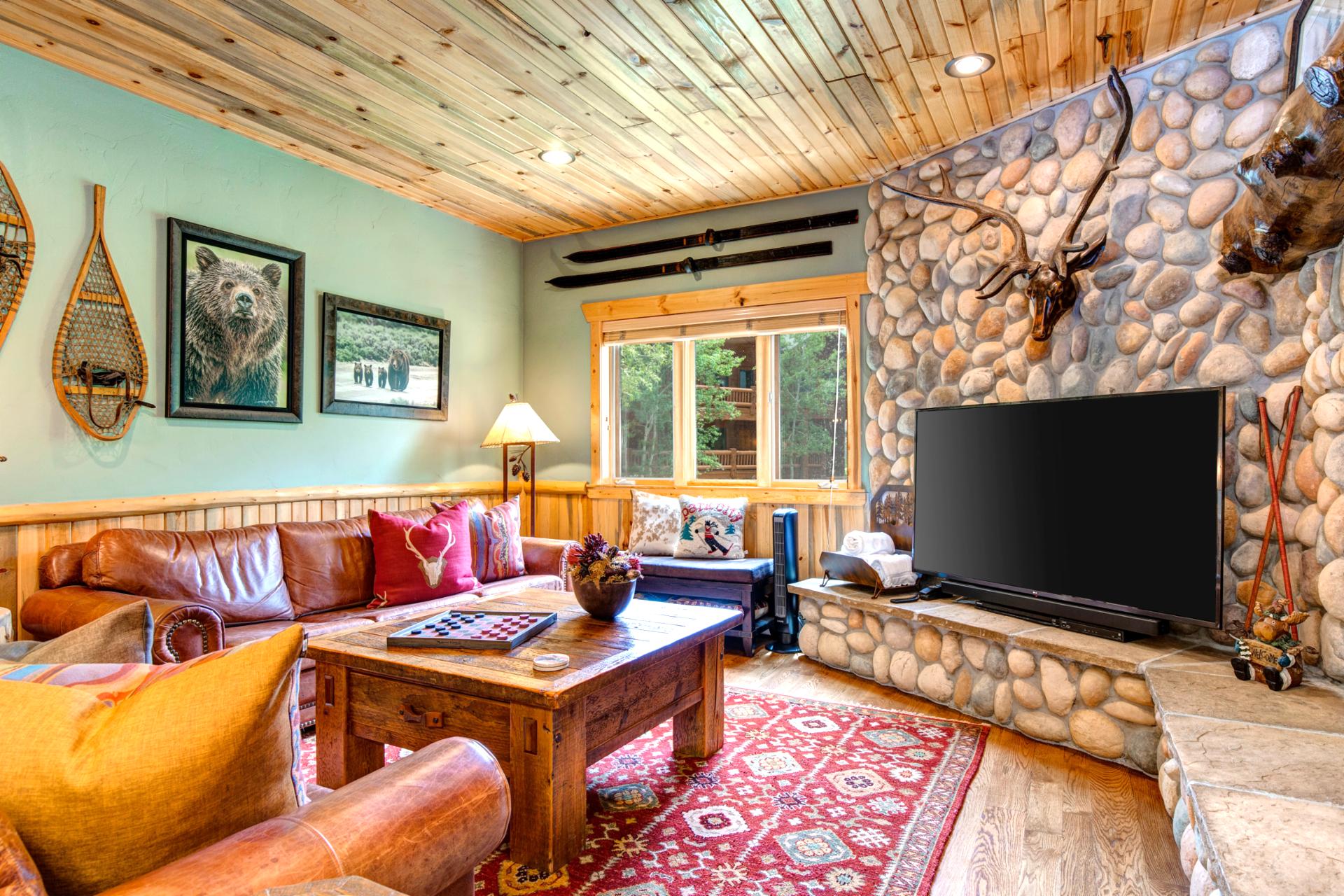 Lodge-style living room with stone fireplace and comfortable seating is perfect for movie nights or relaxing with friends.