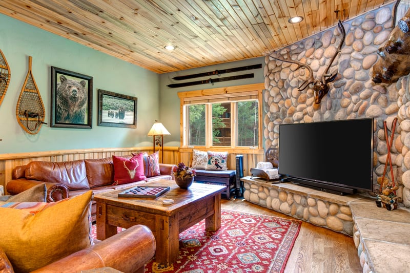 Lodge-style living room with stone fireplace and comfortable seating is perfect for movie nights or relaxing with friends.