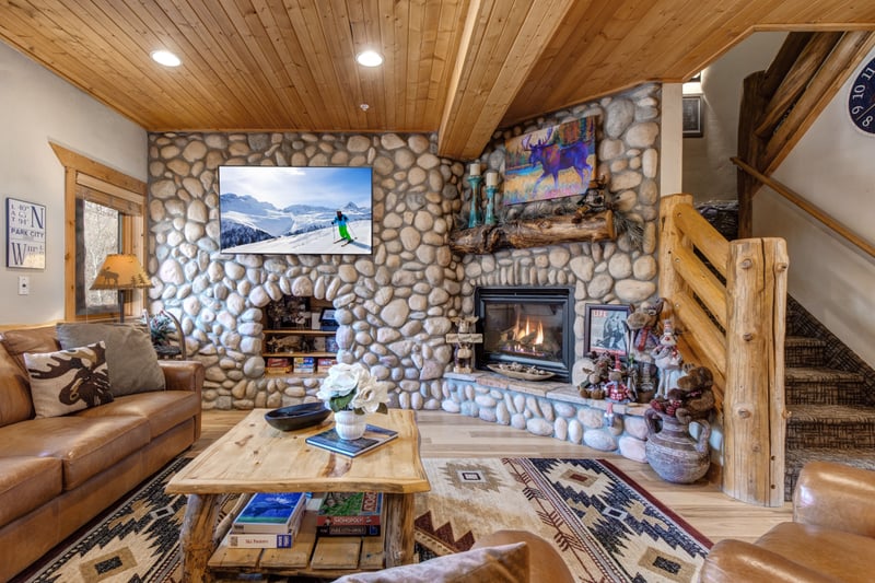 Gather in your lodge-style living room with vaulted ceilings, a large Smart TV, and a cozy stone fireplace.