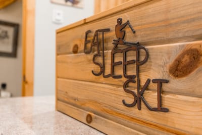 Rustic wooden decor proudly displays motto: Eat, Sleep, Ski, Repeat.